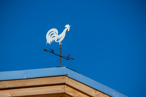 A white metal rooster is placed on the roof as a wind indicator