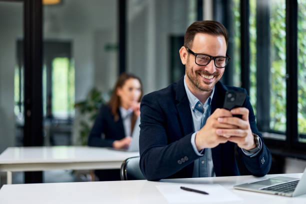 istock A smiling businessman using a mobile phone while working on a laptop. 1500284194