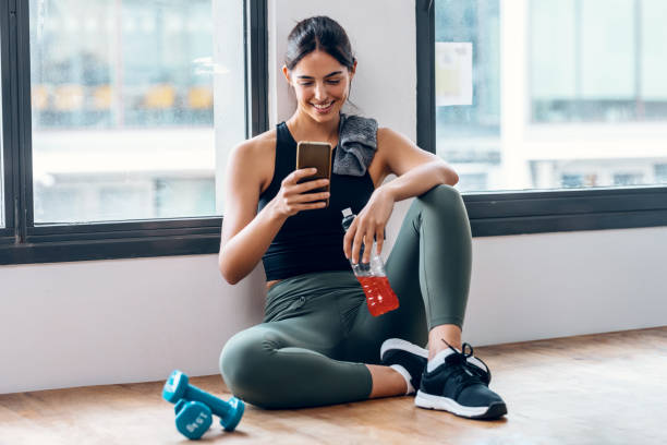 istock Sporty young woman using her mobile phone while holding protein shake after gym exercicis at home 1500285716