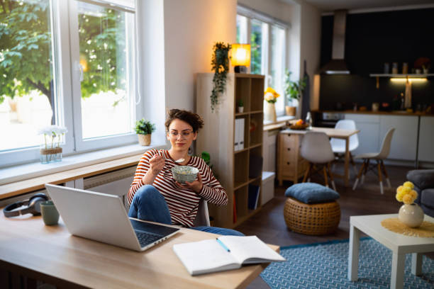 istock Young Caucasian woman eating her breakfast while having an online class over laptop 1500286064