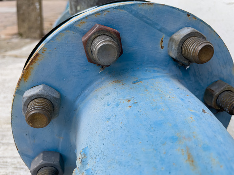 Large sections of pipe converge with bolts holding them securely together.