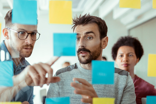 Creative business team looking at sticky notes on glass at start-up company