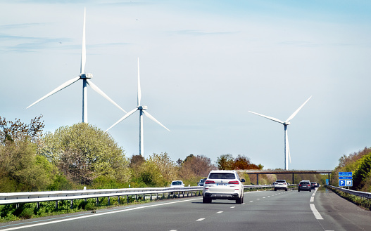 Traffic driving on the autoroute in France along a wind turbone park