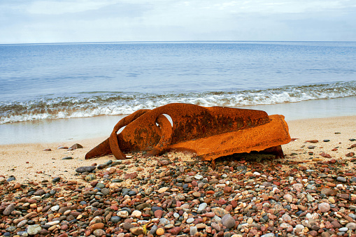 A rusty metal fragment of a ship's side thrown onto the seashore. Consequence of a shipwreck