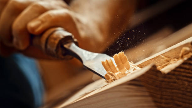 Carpenter shapes wood with chisel Close-up of male carpenter's hand working with chisel in workshop. wood chip stock pictures, royalty-free photos & images