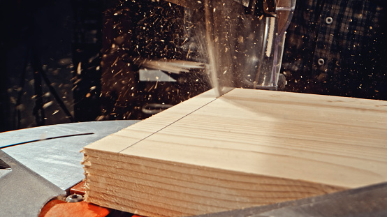 Close-up of circular saw cutting wooden plank in workshop.