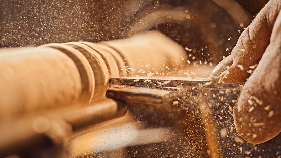 Close-up of man carpenter's hand craft wooden plank in workshop.