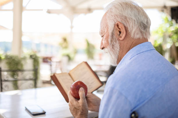 Senior man reading and eating apple