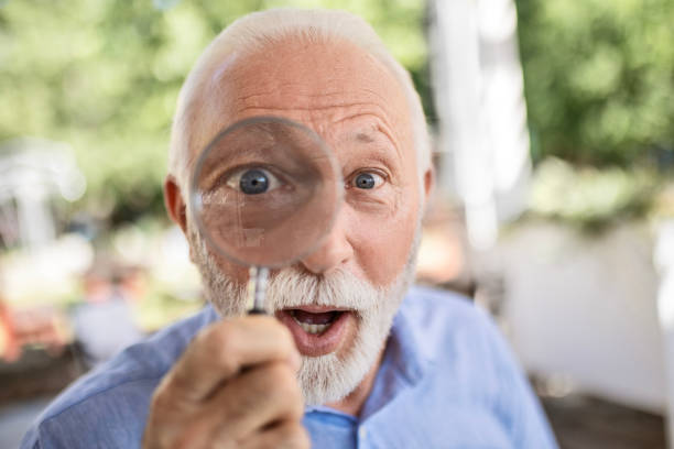 istock Funny senior man with magnifying glass looking at camera 1500294482