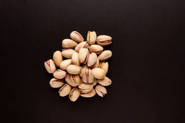 istock A pile of pistachios with shells on a black background. 1500296580
