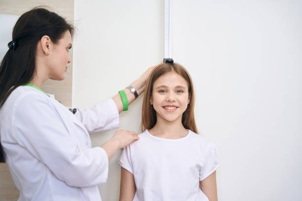 woman nurse checking little girl height using special measuring plank - tall human height women measuring imagens e fotografias de stock