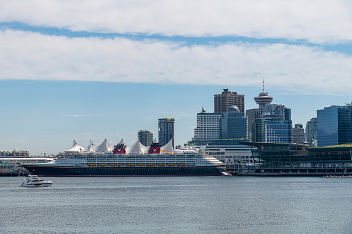 Vancouver, BC, Canada-July 2022; View towards Canada Place with fabric roofs resembling sails, the Convention Centre, Hotel and World Trade Centre and cruise ship in front of the cruise terminal