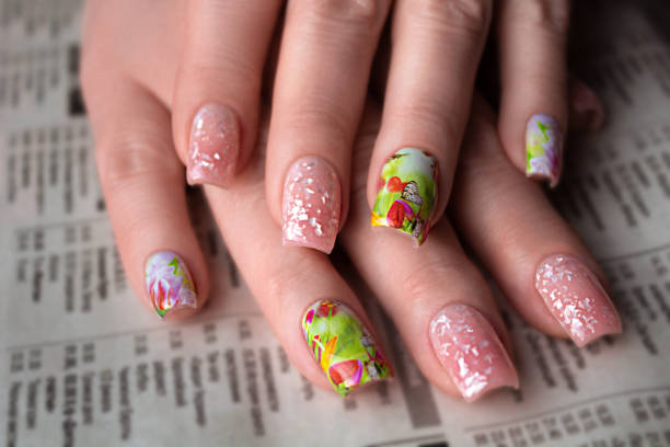 istock Light spring manicure with a sticker with a floral pattern and a gel polish with a shimmer on the background of a newaspaper for women 50+ 1500300720