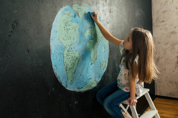 ragazza che disegna la forma del pianeta terra con i gessetti colorati - paintings child house childhood foto e immagini stock