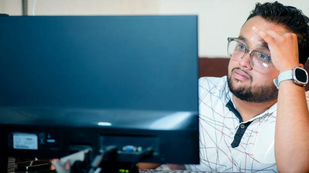 Stressed young businessman working on computer in the office.