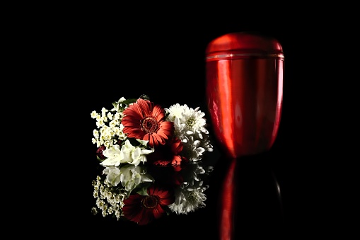 Funeral mourning urn next to a flower bouquet.