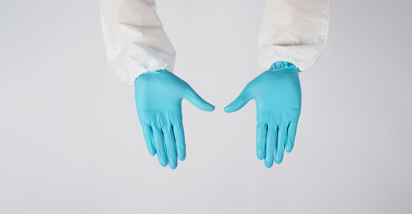 Empty two hands wear blue latex gloves and PPE suite on white background.