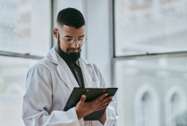 istock A young male doctor stands while looking down at a medical document and reading, with copy space. Stock photo 1500306754