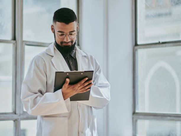 istock A young male doctor facing the front stands smiling while signing a medical document with copy space. Stock photo 1500306757