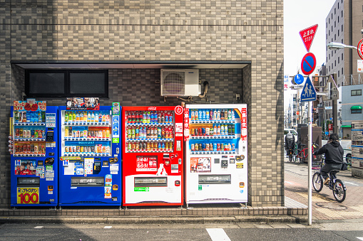 Tokyo, Japan - A cyclist passing a group of drink vending machines in the Sumida district of Tokyo, with both hot and cold drinks available.