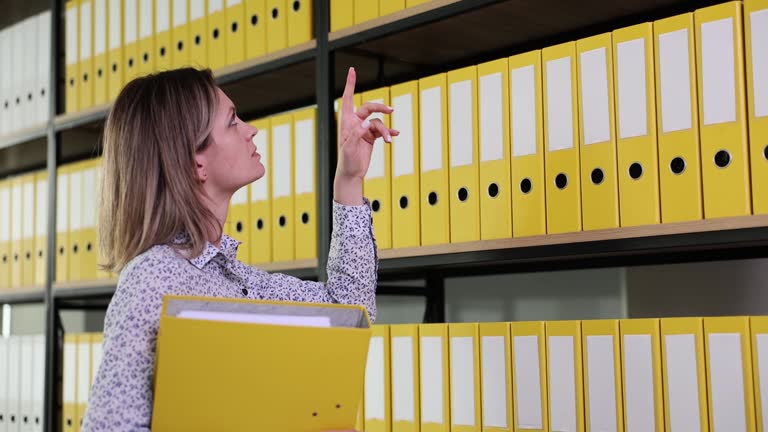 Pensive woman looks at cabinet with folder of documents