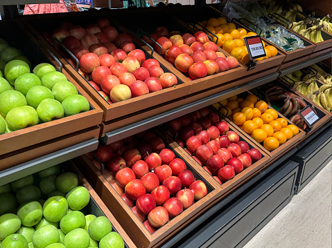 Stock photo showing interior of a supermarket with shelving rack of wooden drawers containing fresh fruit produce.