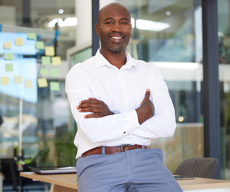 Portrait, business smile and black man with arms crossed in office with pride for career, job or occupation. Ceo, boss and happy, proud and confident male entrepreneur from Kenya with success mindset