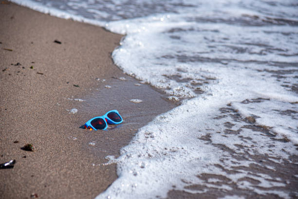 Kolorowe okulary przeciwsłoneczne porzucone na piaszczystej plaży nad morzem – zdjęcie
