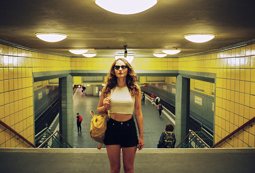 Confident stylish woman in sunglasses standing on platform of u-bahn in Berlin shot on film camera