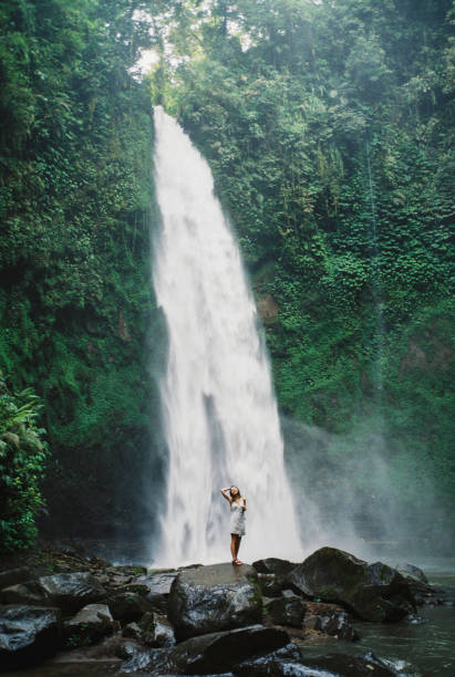 istock Woman standing near refreshing waterfall on Bali 1500314793