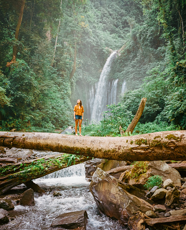 Woman on the log near  near the refreshing waterfall on Bali