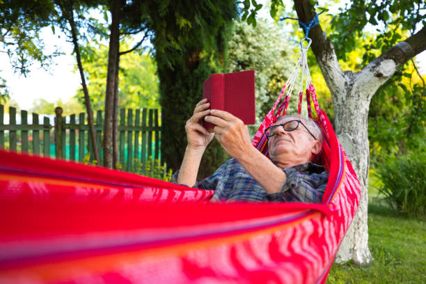 istock Senior man reading book while lying on hammock in garden 1500316592