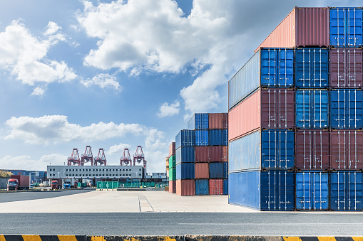 Stacked containers and pavement and buildings at port. Commercial pier landscape on a sunny summer day