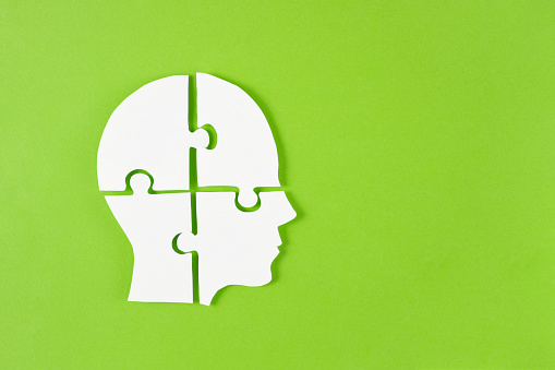 Puzzle head with jigsaw puzzle pieces on green background