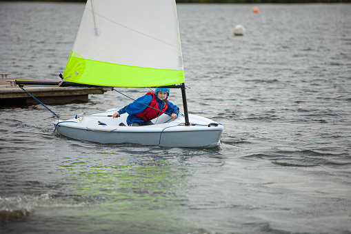 Eleven year old girl, concentrating during a lesson on how to sail a small boat on a lake