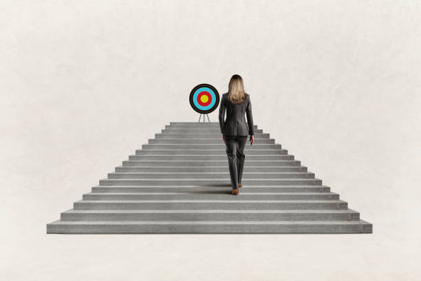 istock Businesswoman Climbing Steps Toward Target 1500336161
