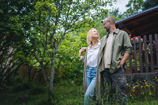 Caucasian happy relaxed middle young age couple enjoying summer in country house standing in garden