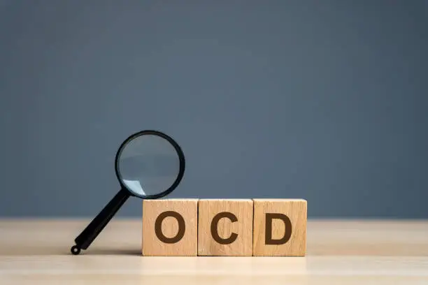 Photo of Wooden blocks with the abbreviation OCD. Obsessive compulsive disease. Mental health and psychiatry concept