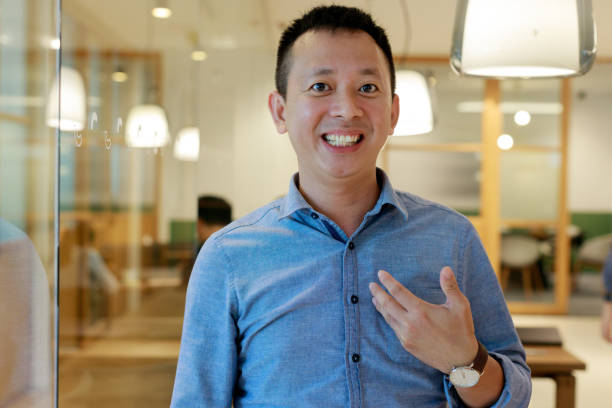 istock Front view of an Asian businessman working in a modern office space, engaging in a video conference with his business partners on a computer while speaking in front of the webcam 1500343358