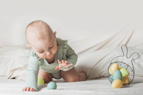istock Baby girl 1 year old on bed with basket and Easter eggs. Egg hunting, kids activity 1500346638