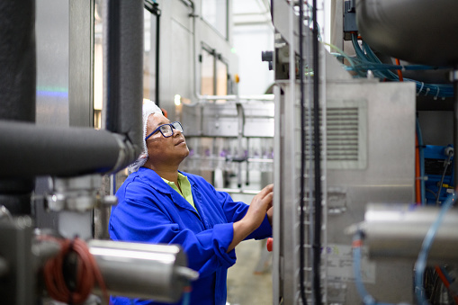 Female Quality Controller wearing protective uniform working in a Water Bottling Plant, Cape Town, South Africa