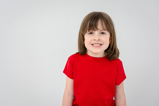 Portrait of a cute happy girl in red t-shirt against white background