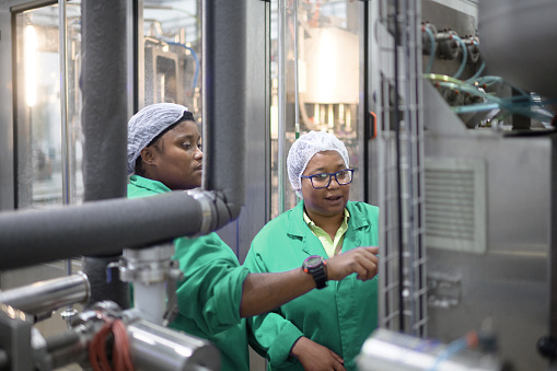 Two females wearing protective uniform working in a Water Bottling Plant, Cape Town, South Africa