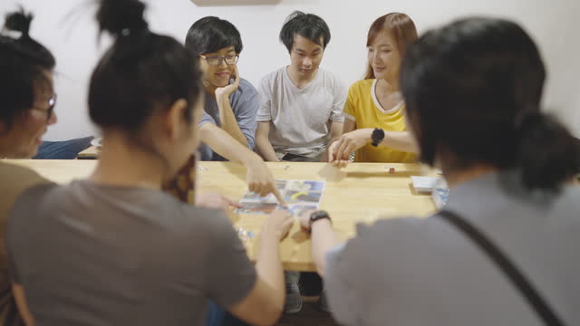 Six friends spend time together in a café playing a funny card game.