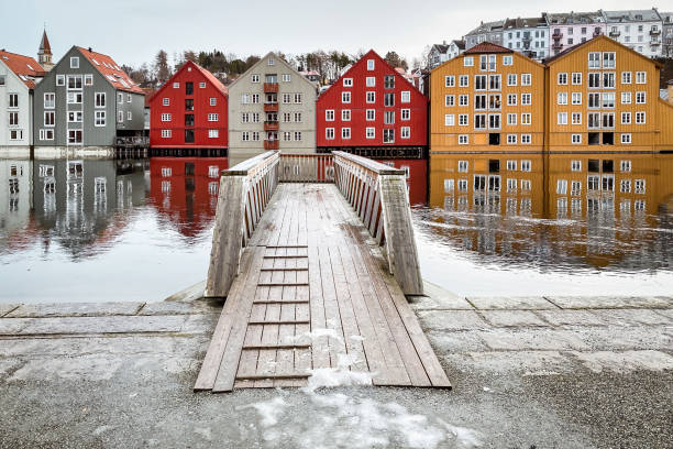 Colorful historic timber storehouses in Trondheim, Norway in winter Colorful historic timber storehouses with Nidelva River in the Brygge district of Trondheim, Norway in winter against cloudy sky stilt house stock pictures, royalty-free photos & images