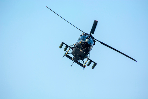Fighter Helicopter is flying against isolated Blue sky.