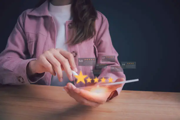 Photo of Close up woman hand using digital tablet or smartphone with popup five star icon for feedback review satisfaction service. Customer service experience and business satisfaction survey.