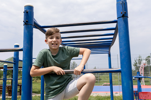 A boy is climbing at the playground. Monkey bars are so much fun!