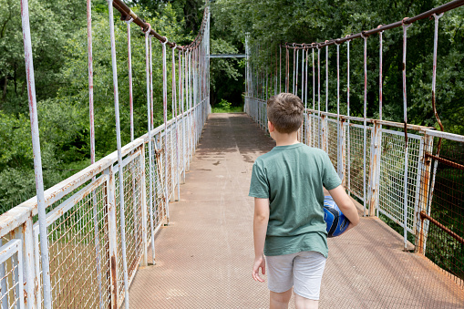 A boy with crosses the bridge after football training.