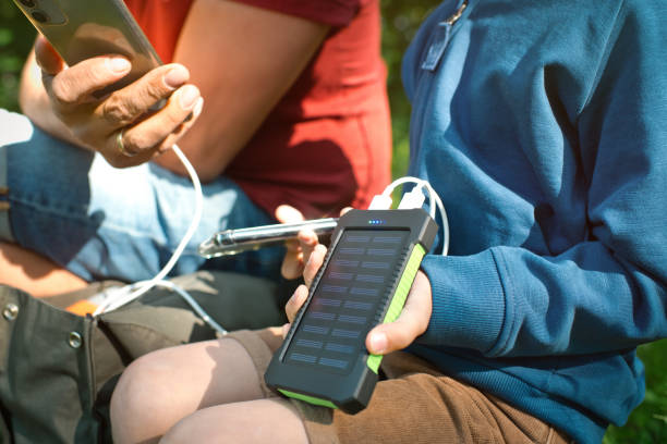 der kleine junge und sein vater verwenden tragbare solarbatterien, um smartphones in der natur aufzuladen. nachhaltiger lebensstil, ökologische alternative energien und ökologische konzepte. - energy fuel and power generation futuristic solar energy stock-fotos und bilder